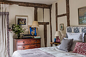 Double bed and antique chest of drawers in bedroom with wooden beams