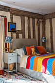 Colourful throw on bed in child's bedroom with half-timbered walls