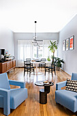 Light blue designer armchairs with side table, retro sideboard and dining area