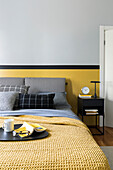 Double bed with grey headboard and yellow bedspread