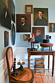 Gemälde mit Portraits an hellblauer Wand im Wohnzimmer