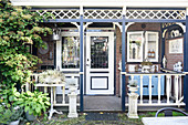 Vintage accessories on veranda adjoining house with pretty front garden