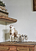 Vintage-style arrangement of old toy sheep on top of antique wooden trunk