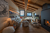 Gemütliche Sofagarnitur, darüber Holzregale im Wohnzimmer mit Dielenboden und Holzdecke