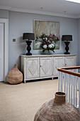 Vase of flowers and two table lamps on sideboard on landing