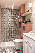 Badezimmer mit Duschbereich, braune Ornamentfliesen an der Wand und auf dem Boden