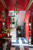 Mahagoni-Tisch in der Diele mit roten Wänden, schwarzem und weißem Marmorboden, Spiegel und Gemälde an der Wand