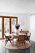 Stühle mit Wiener Geflecht um runden Tisch vor Terrassentür