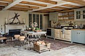 Hellblaue Landhausküche mit Tellerregal und Vintage Tisch mit Hockern vor Kamin