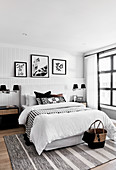Artworks on picture ledge in monochrome bedroom