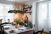 Festively laid table, above it a Christmas wreath with burning candles