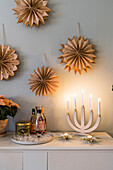 DIY stars made of brown paper above sideboard with candelabra