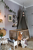 Cot with canopy in nursery with grey walls decorated for Christmas