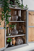 Vintage vases in old, wooden, wall-mounted cupboard