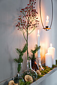 Weihnachtlich dekoriertes Regal mit Vasen, Zweigen und Kerzen