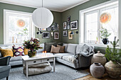 Coffee table, sofa, gallery of photos and rustic urns in cosy living room