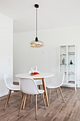 White shell chair at round table in front of display cabinet in dining room