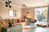 Hellbrauner Polstersofa und Vintage Holztruhe als Couchtisch im Wohnzimmer mit Terrassenzugang