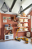 Children's play room with a kitchen, shelves, and toys with terracotta painted wall