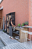 Frau arbeitet in der Outdoor-Küche auf der Terrasse am Backsteinhaus