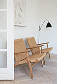 Classic chairs and floor lamp below the sculptural relief on the wall