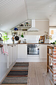 Weiße Einbauküche mit weiß gestrichener Holzdecke