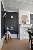 Console table in front of wall with black wood panelling, fireplace and coffered ceiling in the living room