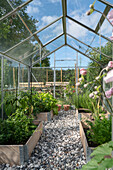 Greenhouse with wooden bed borders and gravel pathway