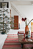 Vintage Couchtisch auf gestreiftem Teppich, im Hintergrund Weihnachtsbaum