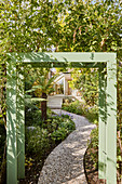 View of gravel garden path see through green-painted pergola