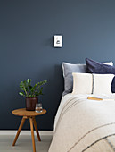 Bed and bedside table against deep blue wall