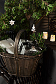 Wooden basket of Christmas presents below conifer branches