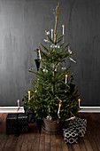 Weihnachtsbaum und Geschenke vor dunkler Wand