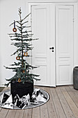 Decorated tree in basket and gift bags in front of interior doors