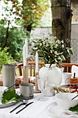 Gedeckter Tisch mit Blumenstrauß auf der Terrasse