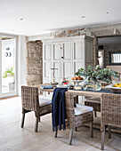 Spacious kitchen-dining room with granite walls, rattan chairs and antique cupboard