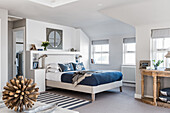 Nautical themed penthouse bedroom with upholstered headboard, cushions and blinds