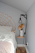 Double bed with rattan headboard, bedside table, and wall lamp