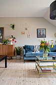 Sideboard, blaues Sofa und Glas-Couchtisch im Wohnzimmer