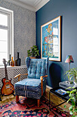 Wingback chair with animal print, guitar next to it in the room with walls in blue tones
