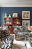 Sofa set with Animal print upholstery in front of glass cabinet in living room with blue wall