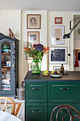 Blick über Küchentheke mit grüner Front auf Bildergalerie