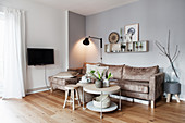 Sand-coloured sofa, wall-mounted lamp and coffee table with vases of white flowers