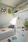 Helles Kinderzimmer mit Bett, Schubladenschrank und Regalen