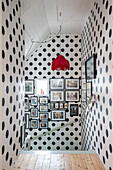 Polka-dot wallpaper on landing with staircase and gallery of pictures on wall
