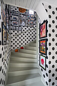 Flur mit grauer Treppe, gepunkteter Tapete und Bildergalerie
