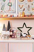 Christmas decorations on pink kitchen cabinet, shelf above