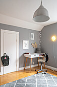 Desk with swivel chair in children's room corner with grey walls
