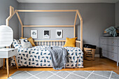 Bed with house-shaped bed frame in children's room with grey walls