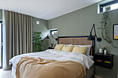 Double bed with headboard in bedroom with green walls